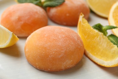 Photo of Tasty mochi, cut orange and mint on plate, closeup