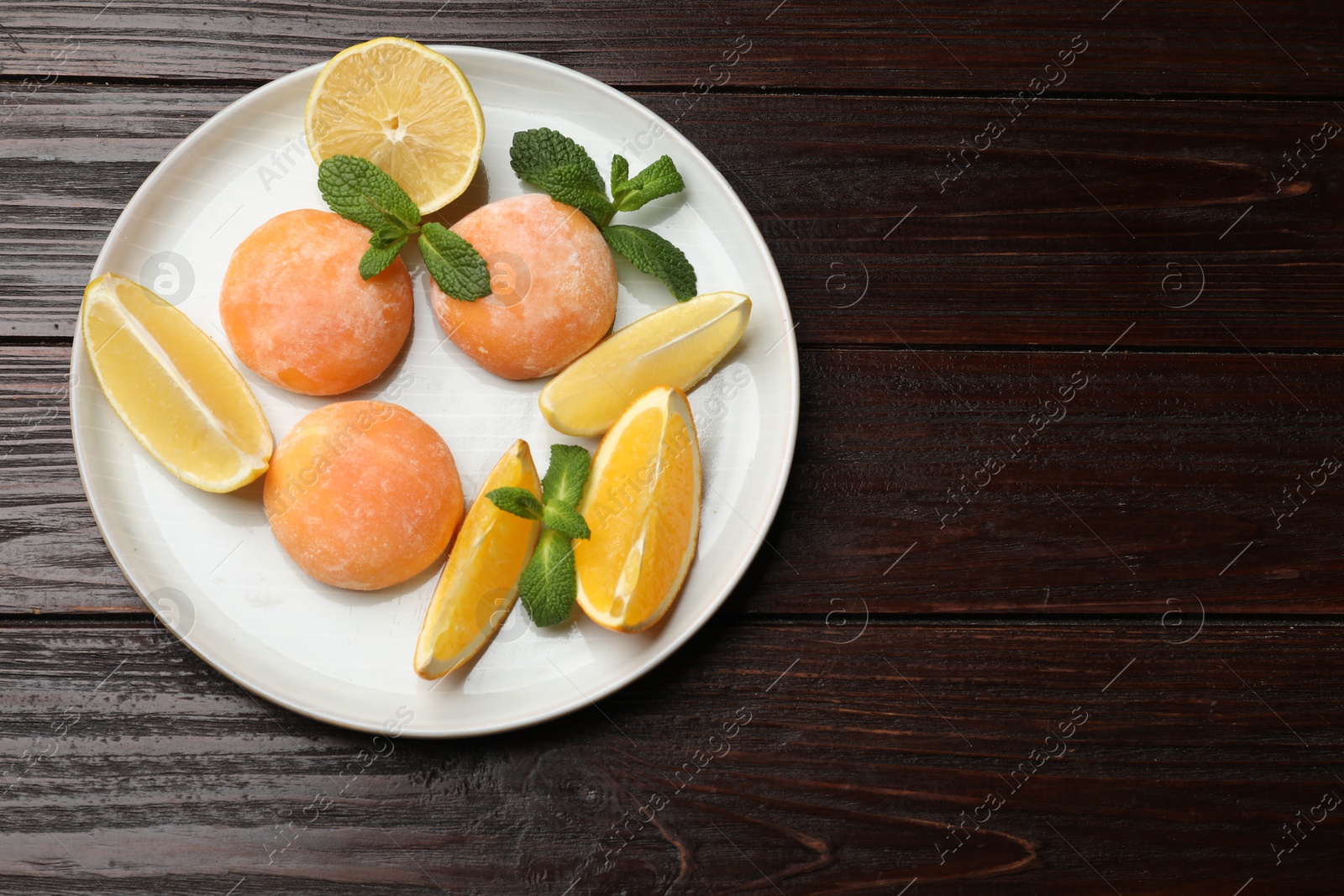 Photo of Plate with tasty mochi, cut orange, lemon and mint on wooden table, top view. Space for text