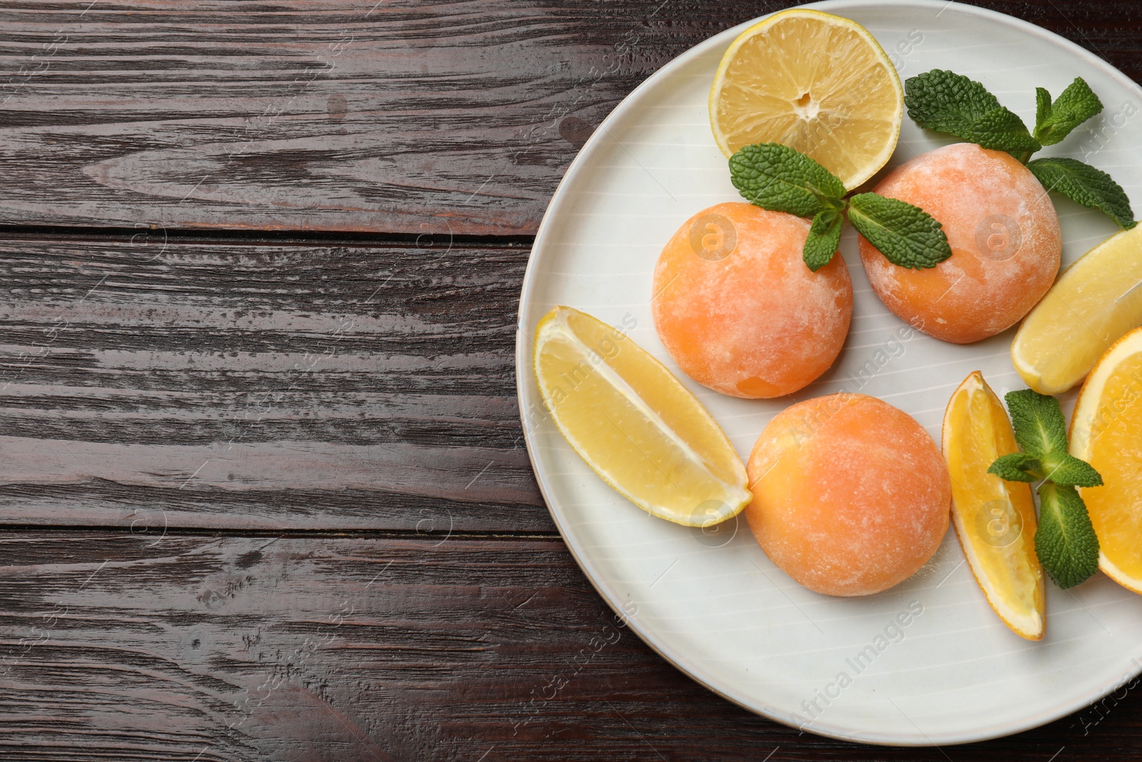 Photo of Plate with tasty mochi, cut orange, lemon and mint on wooden table, top view. Space for text