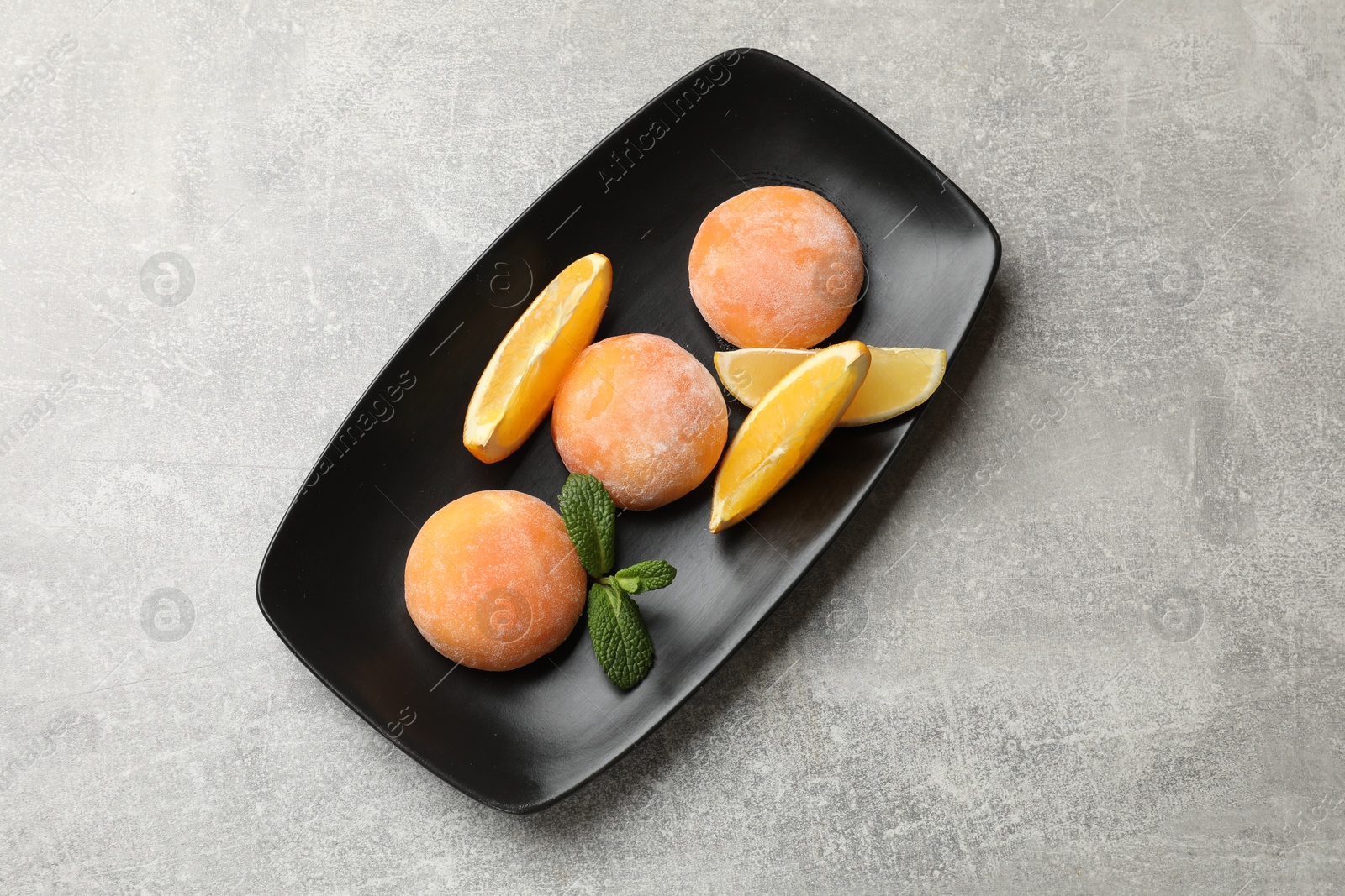 Photo of Tasty mochi, cut orange and mint on grey textured table, top view