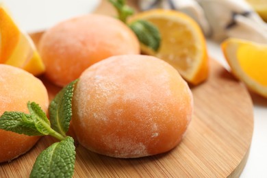 Photo of Board with tasty mochi and mint on table, closeup