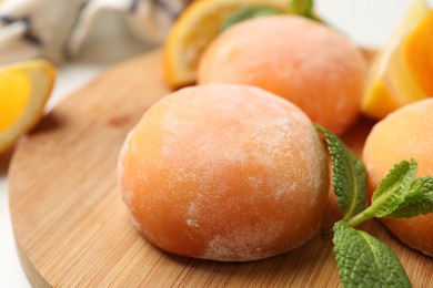 Photo of Board with tasty mochi and mint on table, closeup