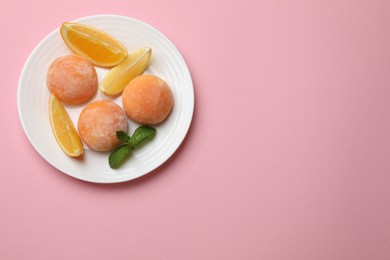 Photo of Plate with tasty mochi, cut orange and mint on pink table, top view. Space for text