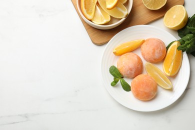 Photo of Plate with tasty mochi, cut orange, lemon and mint on white marble table, flat lay. Space for text