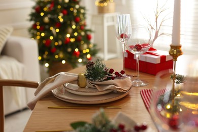 Photo of Christmas place setting with festive decor on wooden table in room