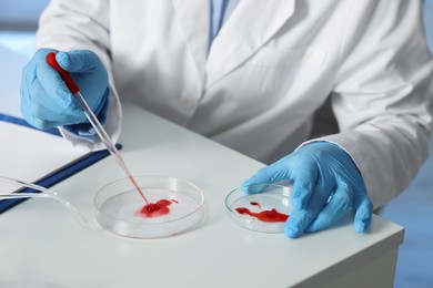 Photo of Laboratory testing. Doctor dripping blood sample into Petri dish indoors, closeup