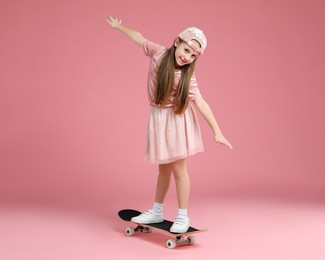 Photo of Little girl standing on skateboard against pink background