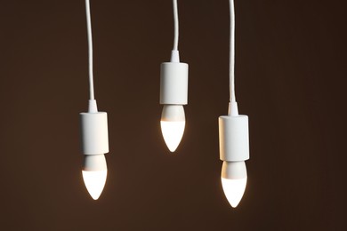 Photo of Light bulbs hanging on cords against brown background