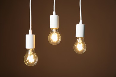 Photo of Light bulbs hanging on cords against brown background