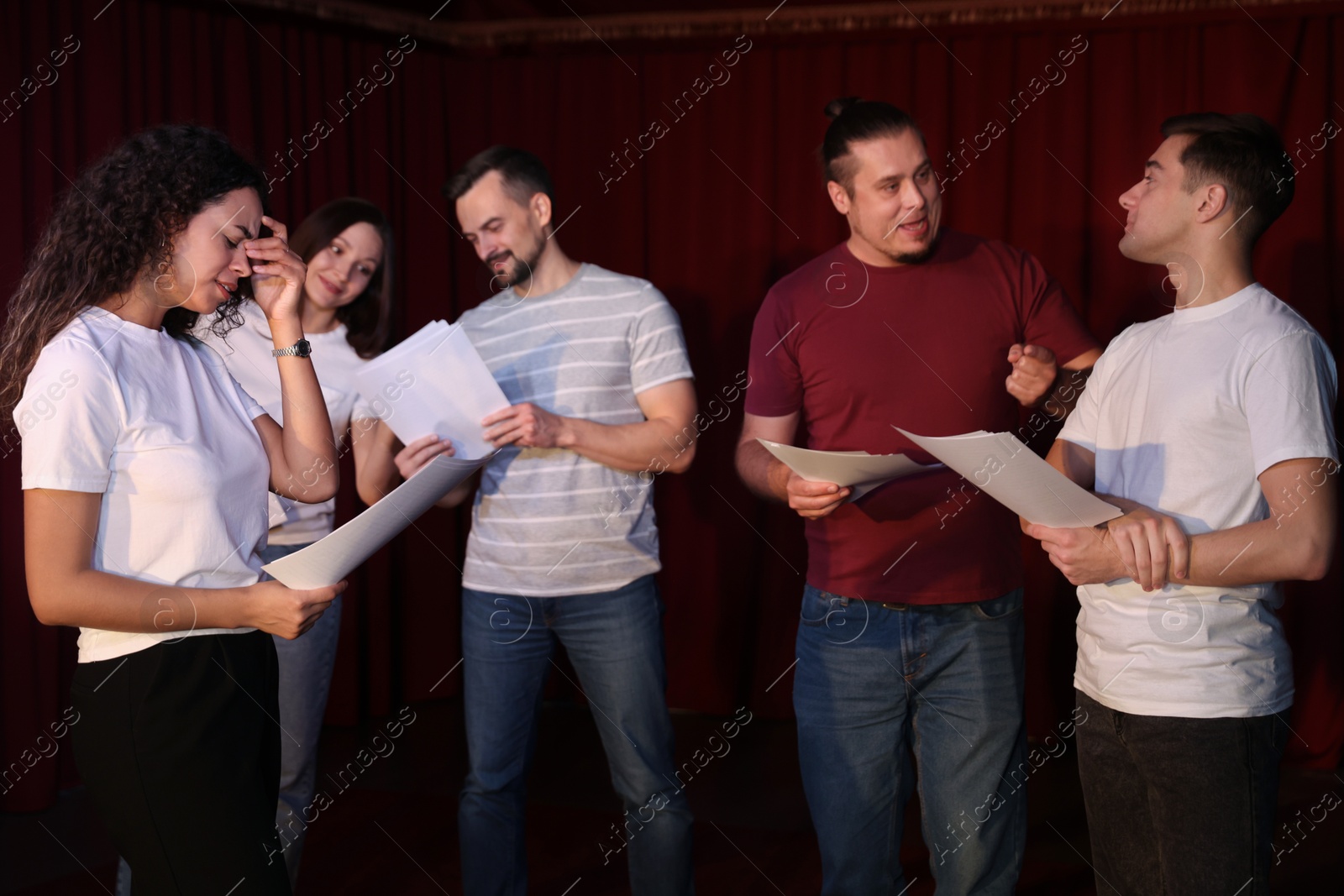 Photo of Professional actors with their scripts rehearsing in theatre