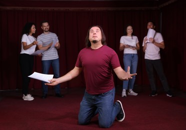 Photo of Professional actors with their scripts rehearsing in theatre