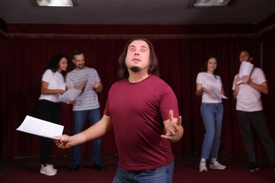 Professional actors with their scripts rehearsing in theatre