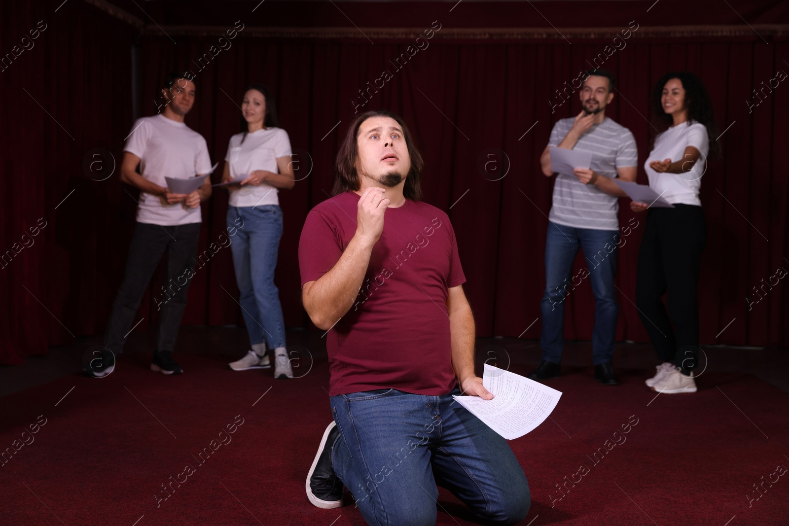 Photo of Professional actors with their scripts rehearsing in theatre