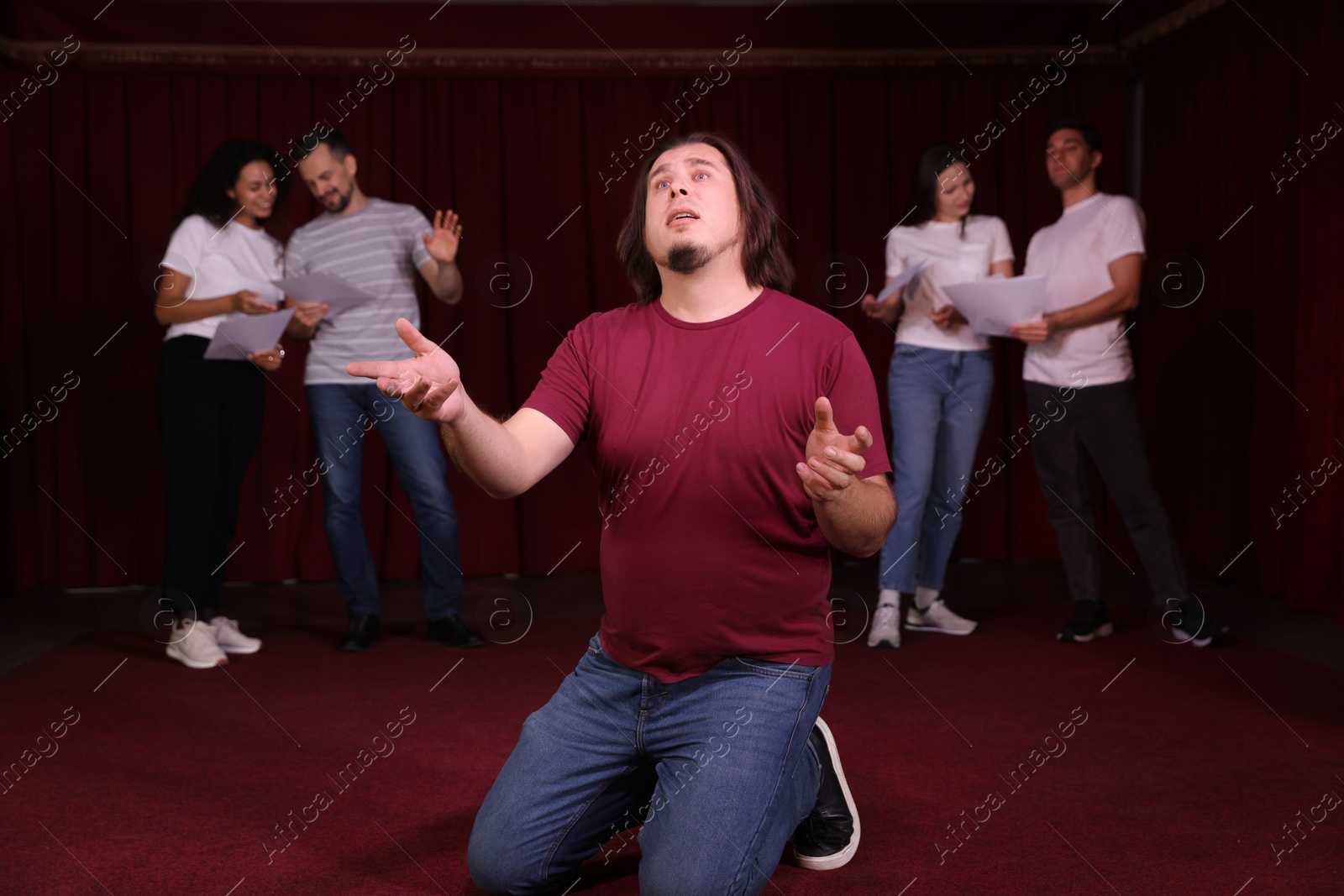 Photo of Professional actors with their scripts rehearsing in theatre