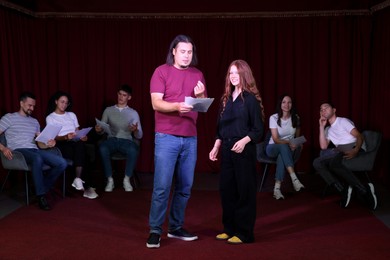 Professional actors with their scripts rehearsing in theatre