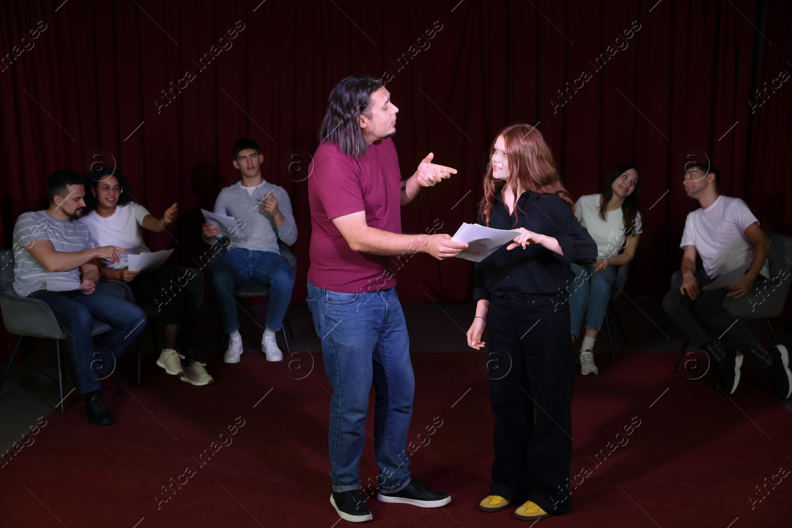 Photo of Professional actors with their scripts rehearsing in theatre