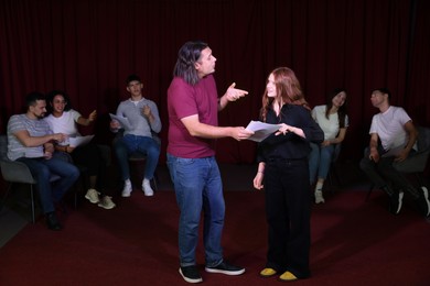 Professional actors with their scripts rehearsing in theatre