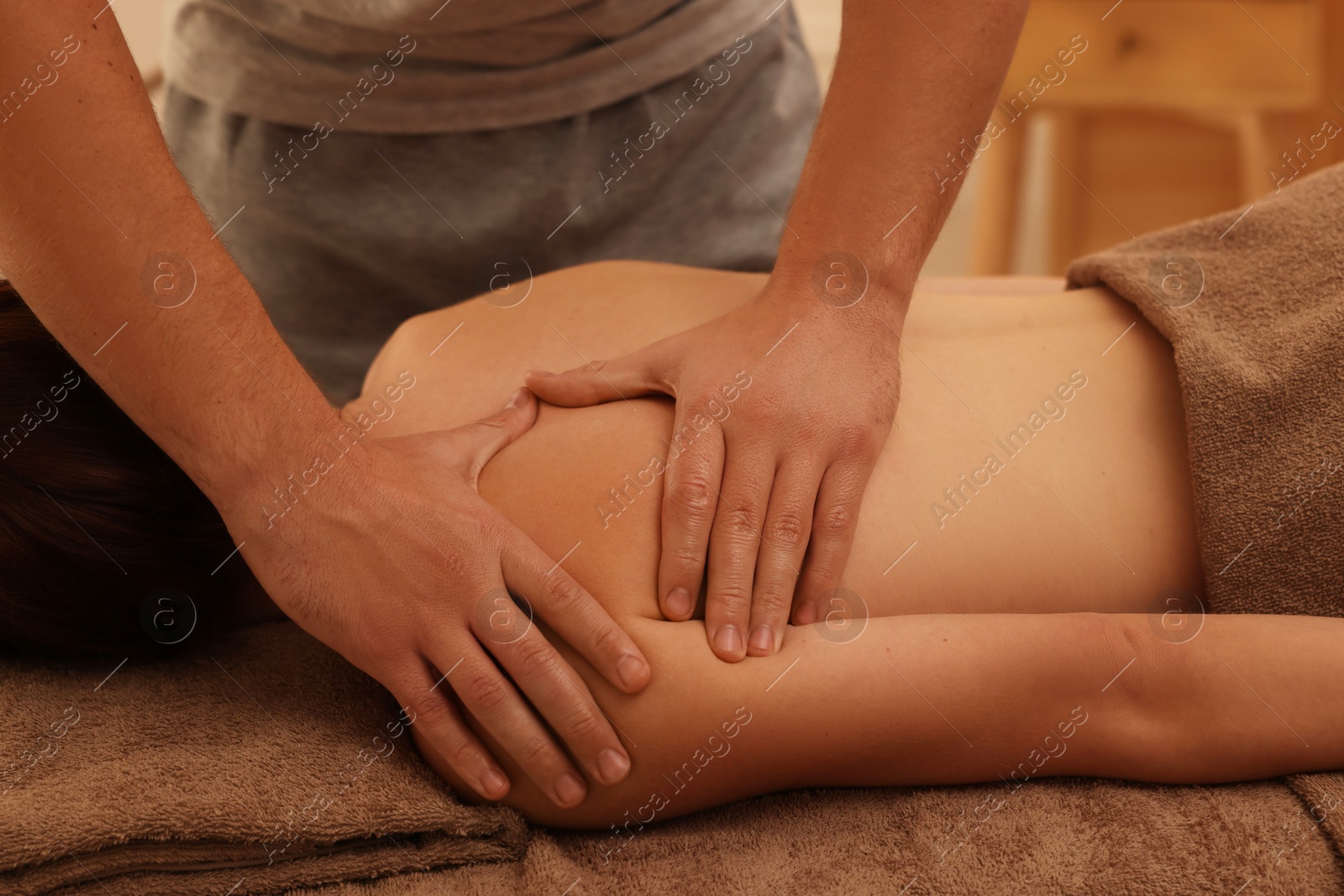 Photo of Osteopath massaging woman's back on couch indoors, closeup. Manual therapy