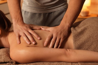 Photo of Osteopath massaging woman's back on couch indoors, closeup. Manual therapy