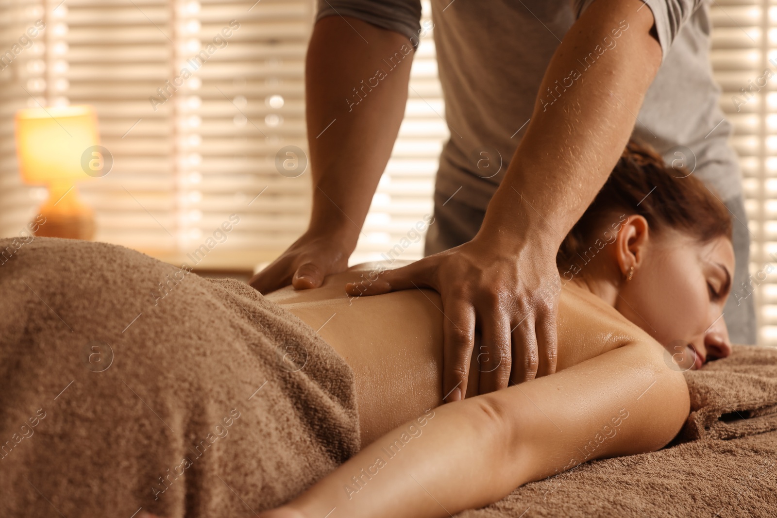 Photo of Osteopath massaging woman's back on couch indoors, closeup. Manual therapy