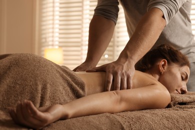 Photo of Osteopath massaging woman's back on couch indoors, closeup. Manual therapy