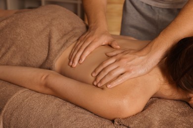 Osteopath massaging woman's back on couch indoors, closeup. Manual therapy