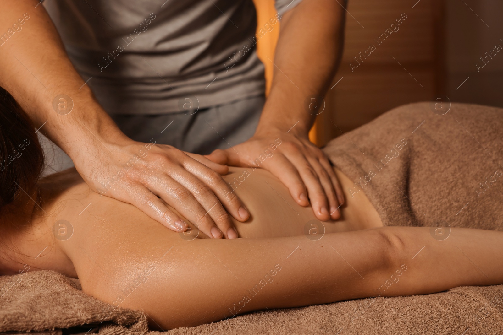 Photo of Osteopath massaging woman's back on couch indoors, closeup. Manual therapy