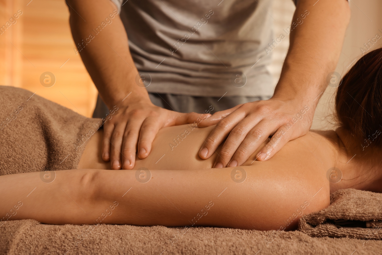 Photo of Osteopath massaging woman's back on couch indoors, closeup. Manual therapy