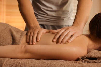 Photo of Osteopath massaging woman's back on couch indoors, closeup. Manual therapy