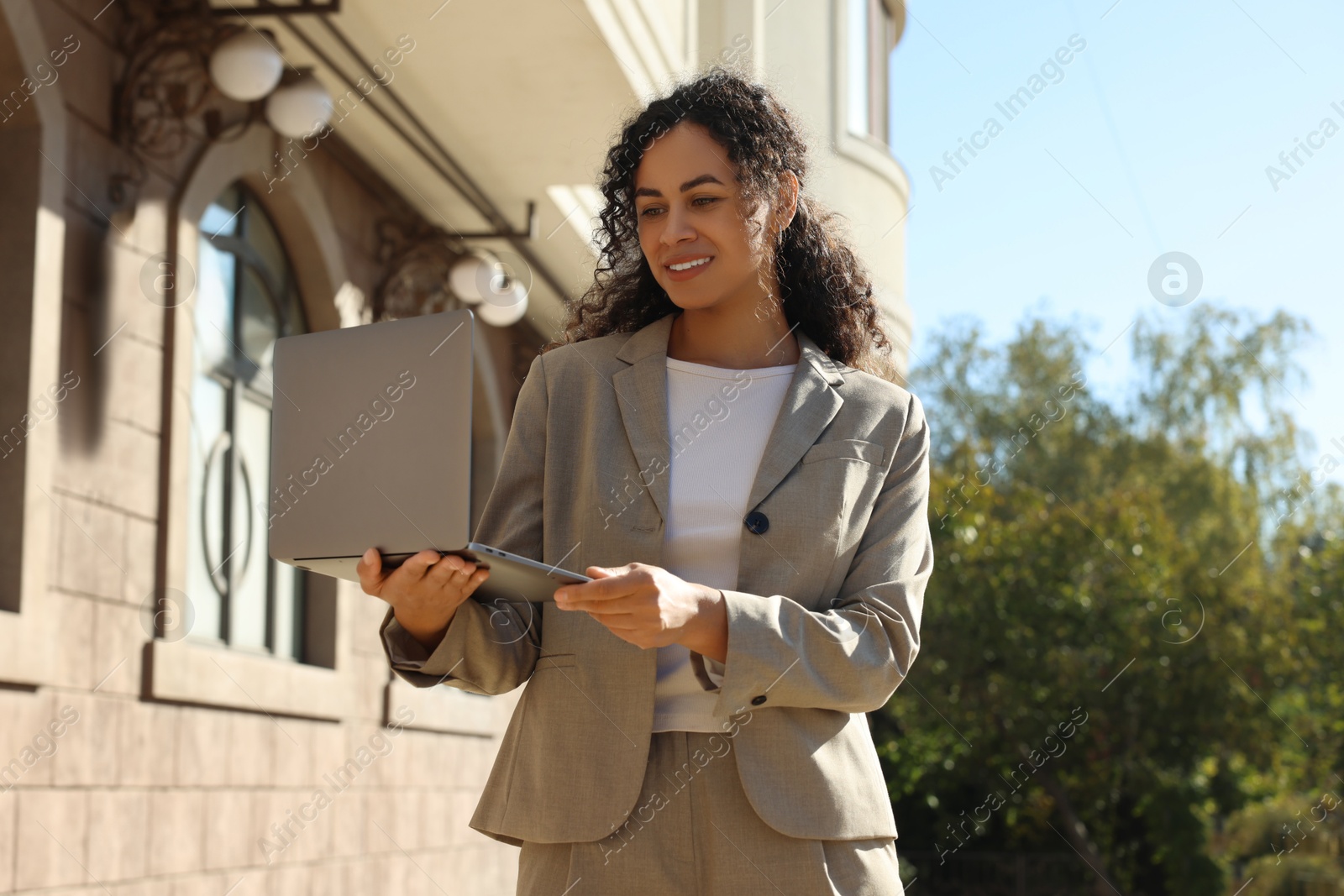 Photo of Portrait of young woman with laptop wearing stylish suit outdoors