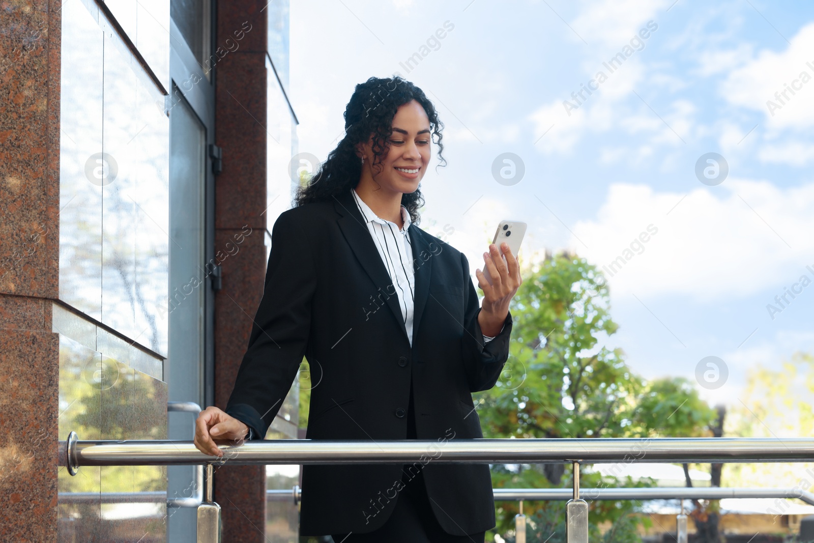 Photo of Portrait of young woman with phone wearing stylish suit outdoors