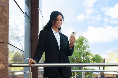 Photo of Portrait of young woman with phone wearing stylish suit outdoors