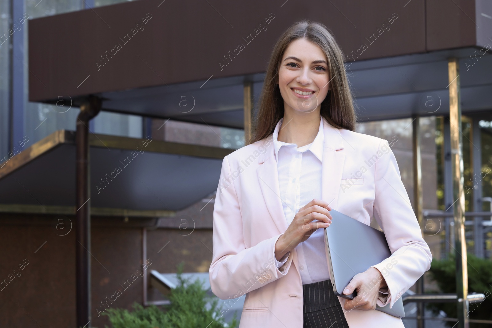 Photo of Portrait of young woman with laptop wearing stylish suit outdoors. Space for text