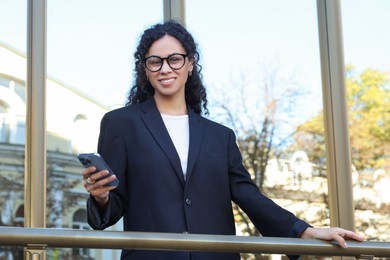 Photo of Portrait of young woman with phone wearing stylish suit outdoors