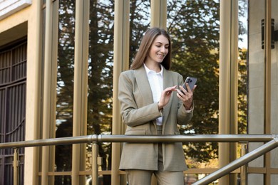 Photo of Portrait of young woman with phone wearing stylish suit outdoors