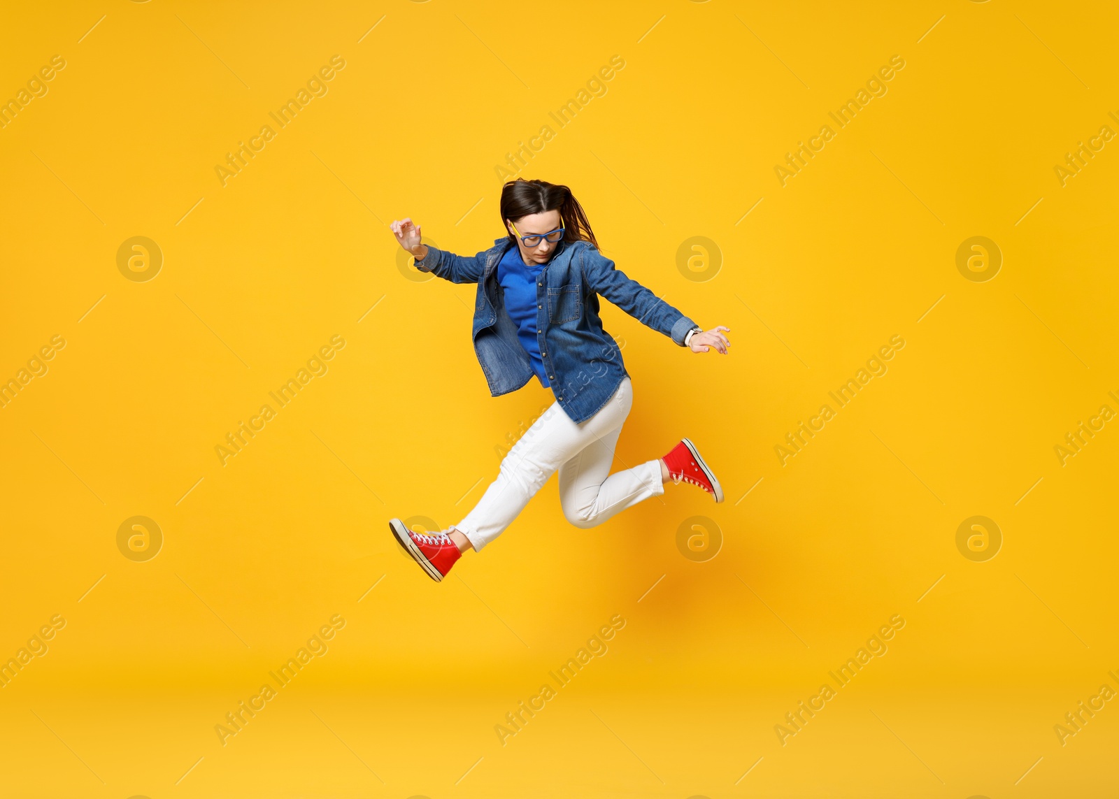 Photo of Beautiful female skater jumping on orange background