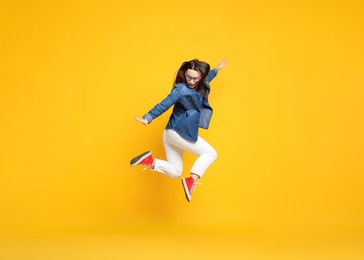 Photo of Beautiful female skater jumping on orange background