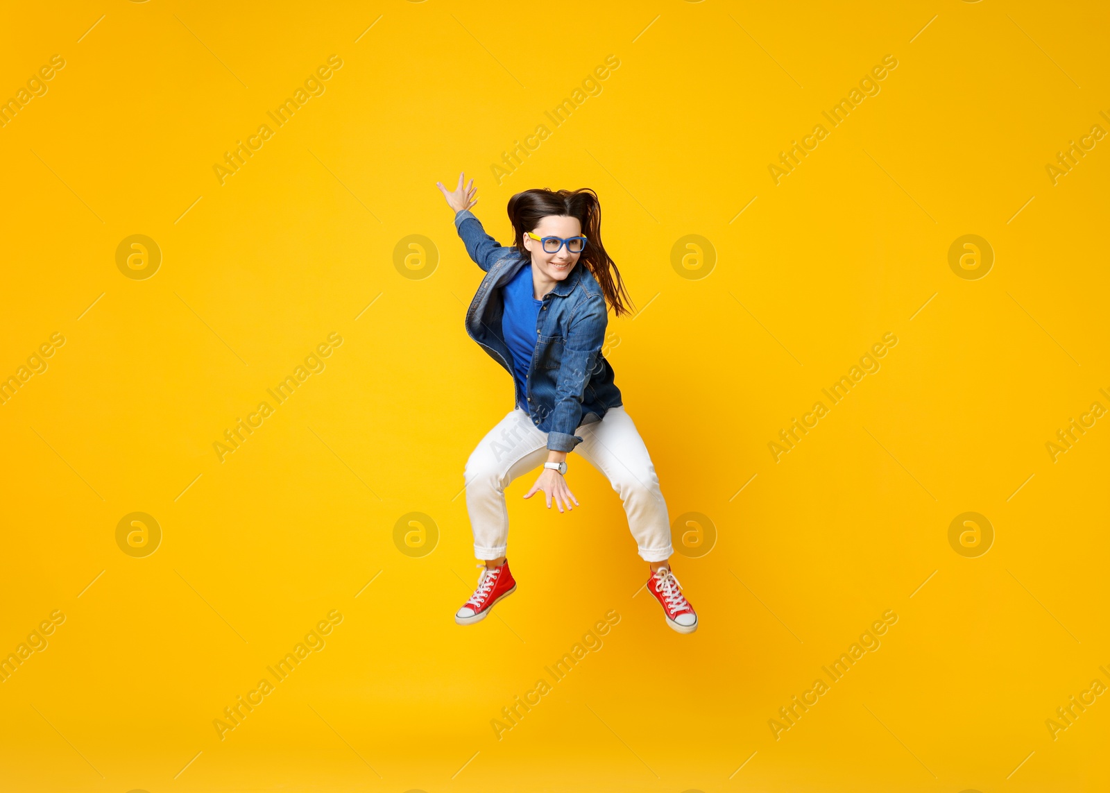 Photo of Smiling female skater jumping on orange background