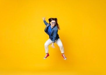 Photo of Smiling female skater jumping on orange background