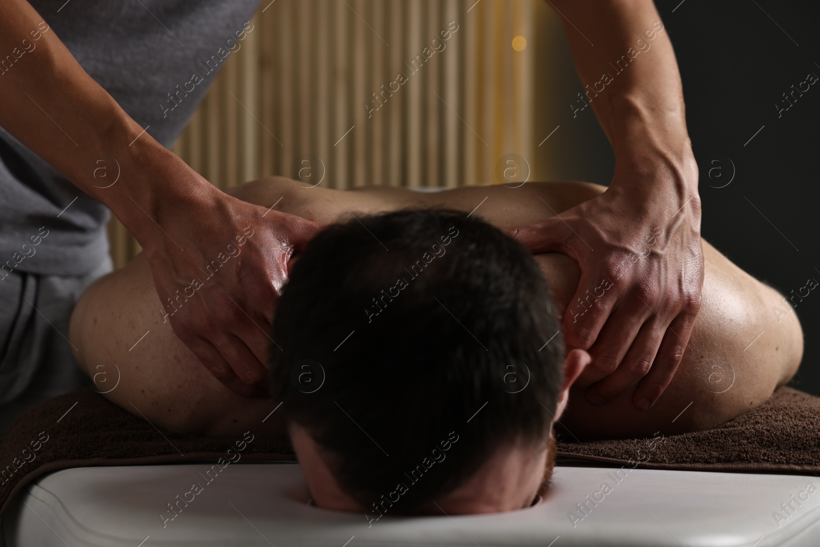 Photo of Professional physiotherapist doing neck massage for his client indoors, closeup