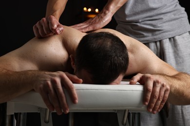 Photo of Professional physiotherapist doing shoulder massage for his client indoors, closeup