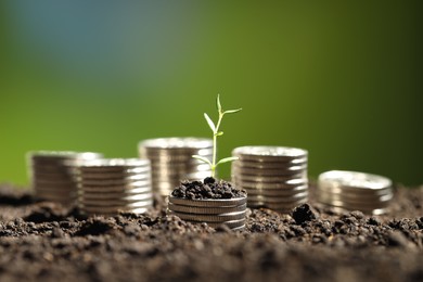 Photo of Money growth concept. Coins with young sprout in soil on green background, closeup. Space for text