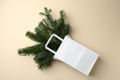 Photo of Christmas bouquet. Green fir tree branches in paper bag on beige background, top view