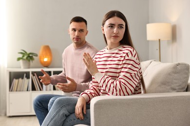 Photo of Tired woman stopping her husband at home. Relationship problems