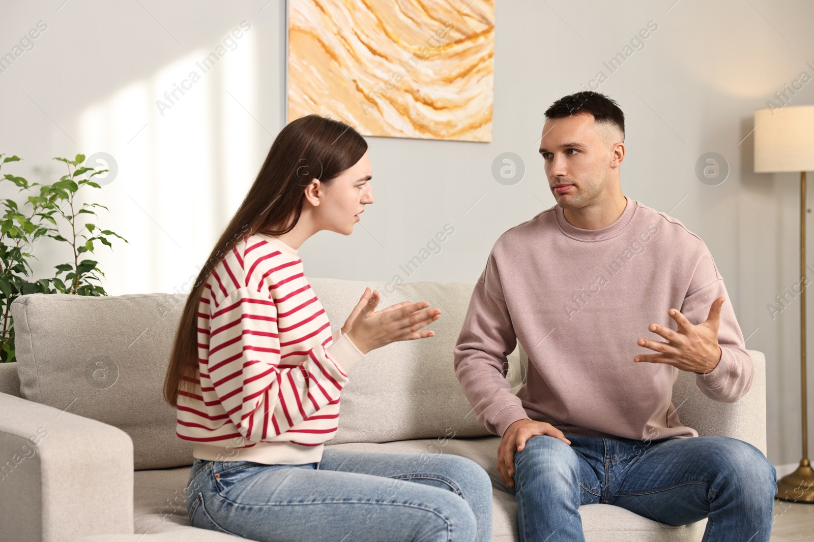 Photo of Young couple arguing on sofa at home