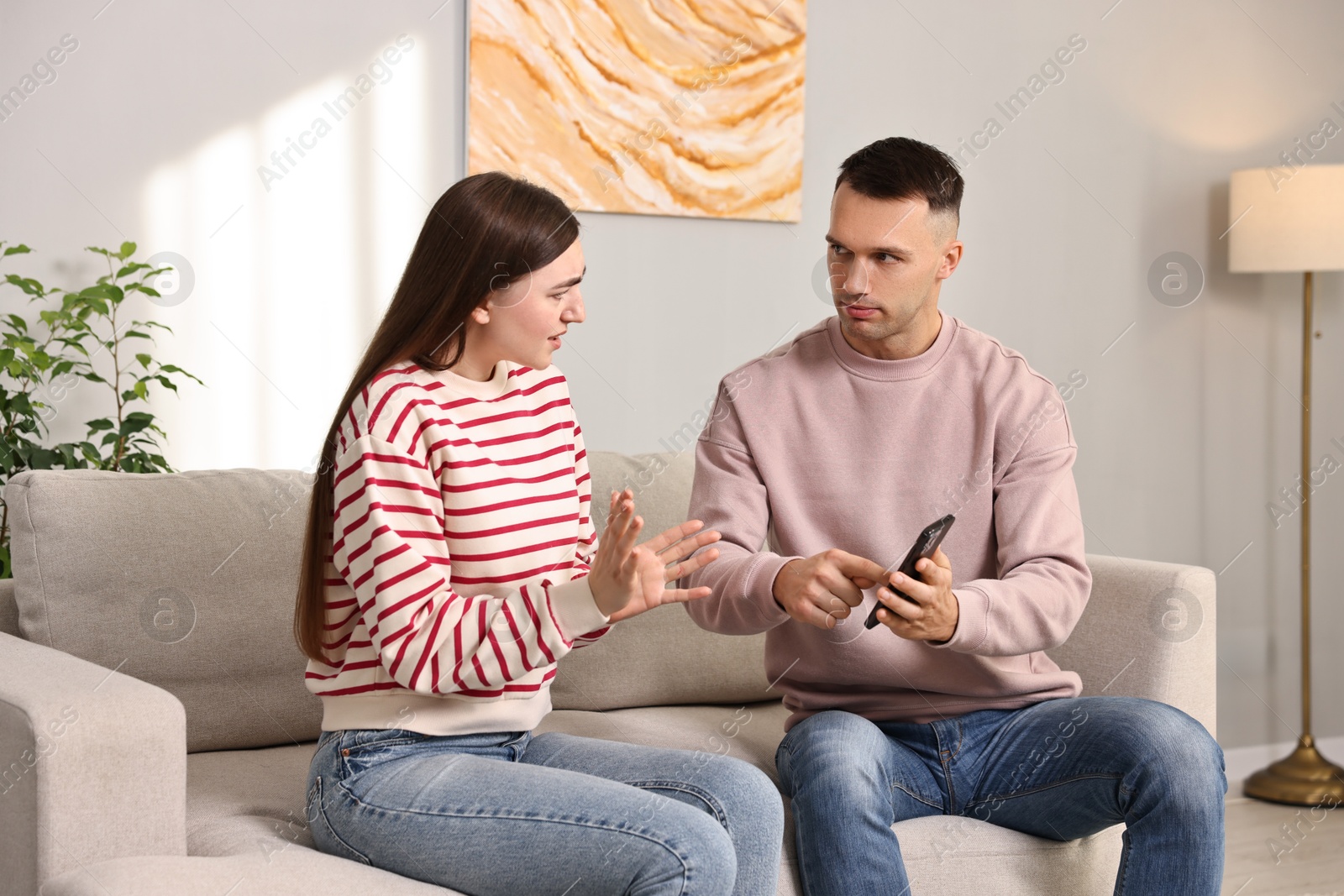 Photo of Husband showing smartphone with proofs to his unfaithful wife at home