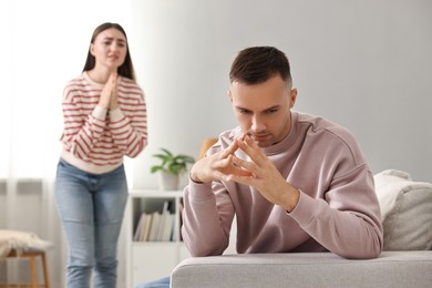 Photo of Wife apologizing her husband while he ignoring her at home, selective focus