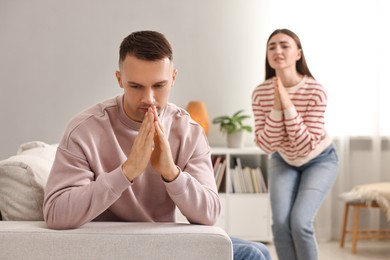 Photo of Wife apologizing her husband while he ignoring her at home, selective focus