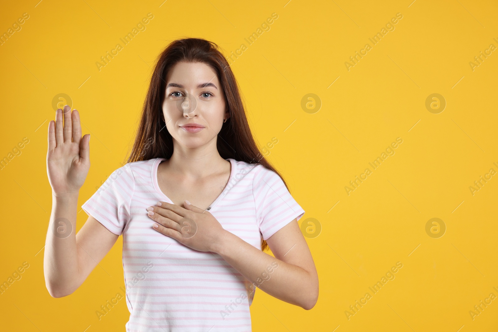 Photo of Woman making promise with raised hand on orange background, space for text. Oath gesture