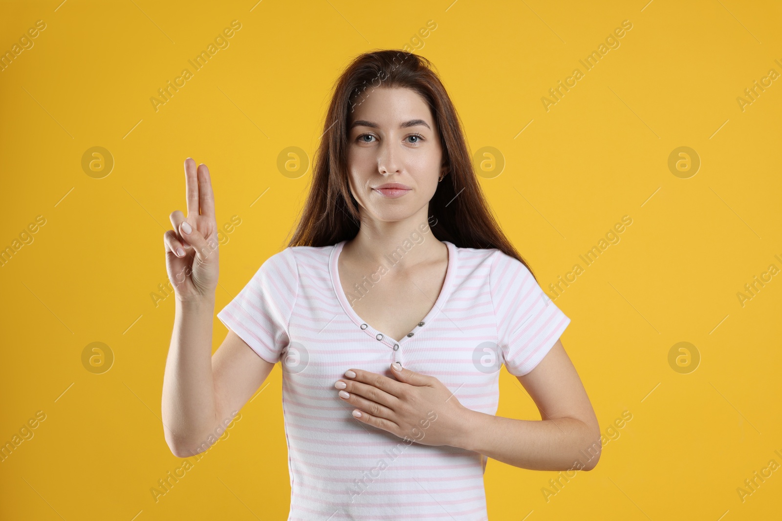 Photo of Woman showing oath gesture on orange background. Making promise